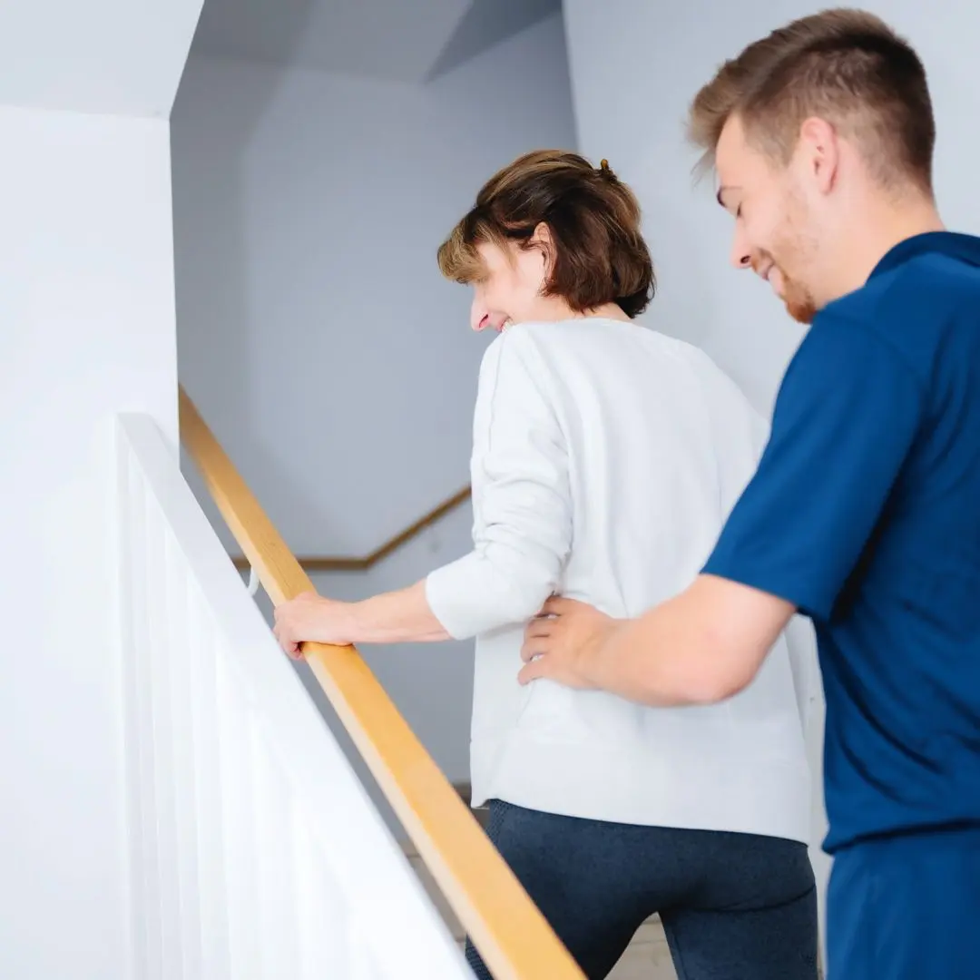 Nico Hanskötter begleitet eine Seniorin sicher die Treppe hinauf